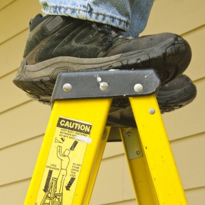Worker standing on top step of a ladder